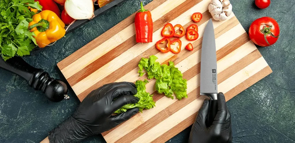 Cuchillo para chef profesional Zwilling J.A. Henckels Four Star siendo utilizado para cortar verduras en una tabla para cortar