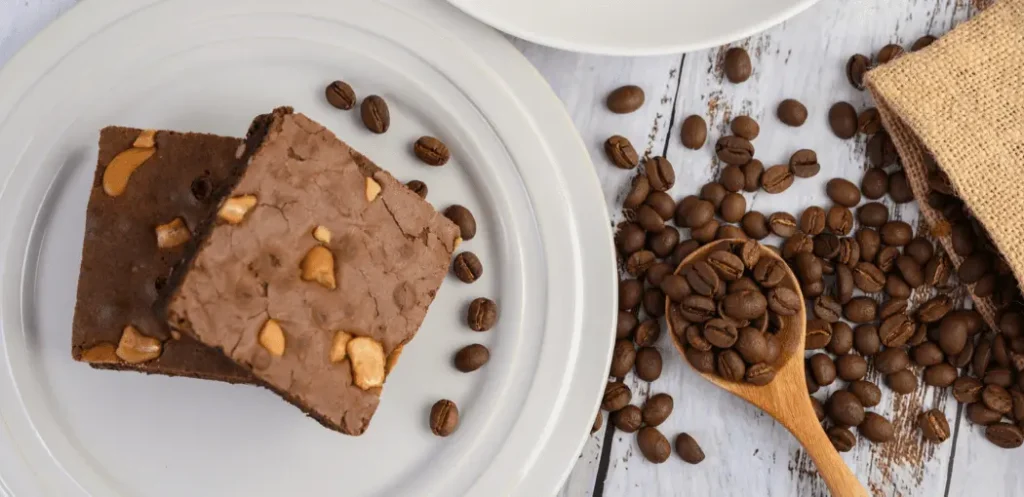 Brownies de café servidos en plato de porcelana con granos de café alrededor
